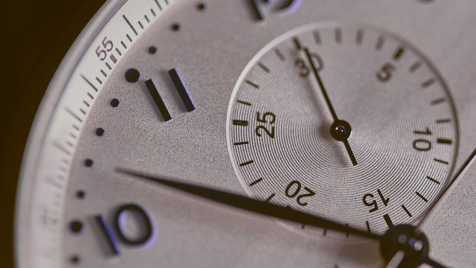 Cadran de montre-bracelet en gros plan, aiguilles et index en relief sous un verre bombé