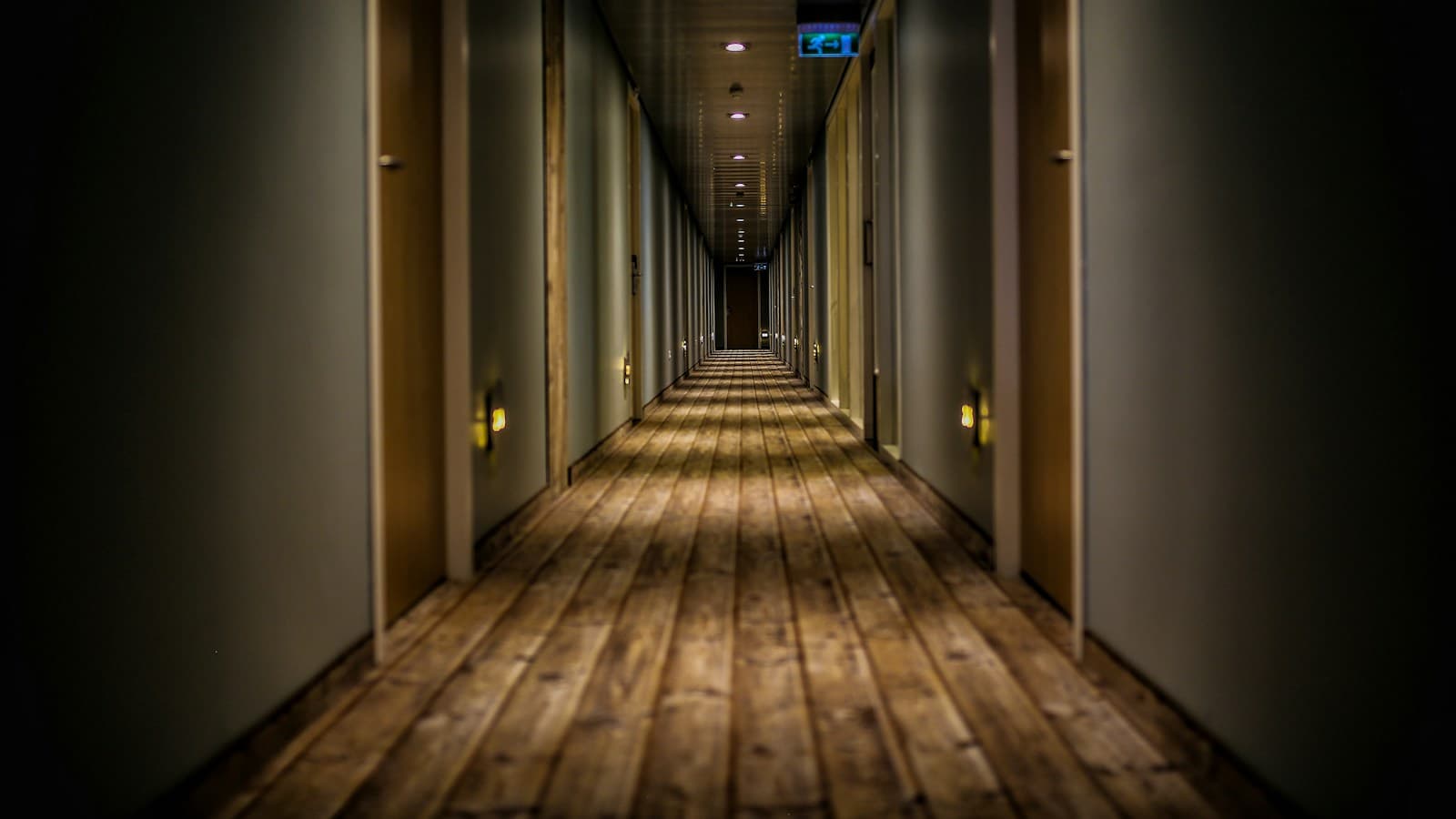Couloir d hotel en enfilade, portes de chambres alignees sous un eclairage tamise