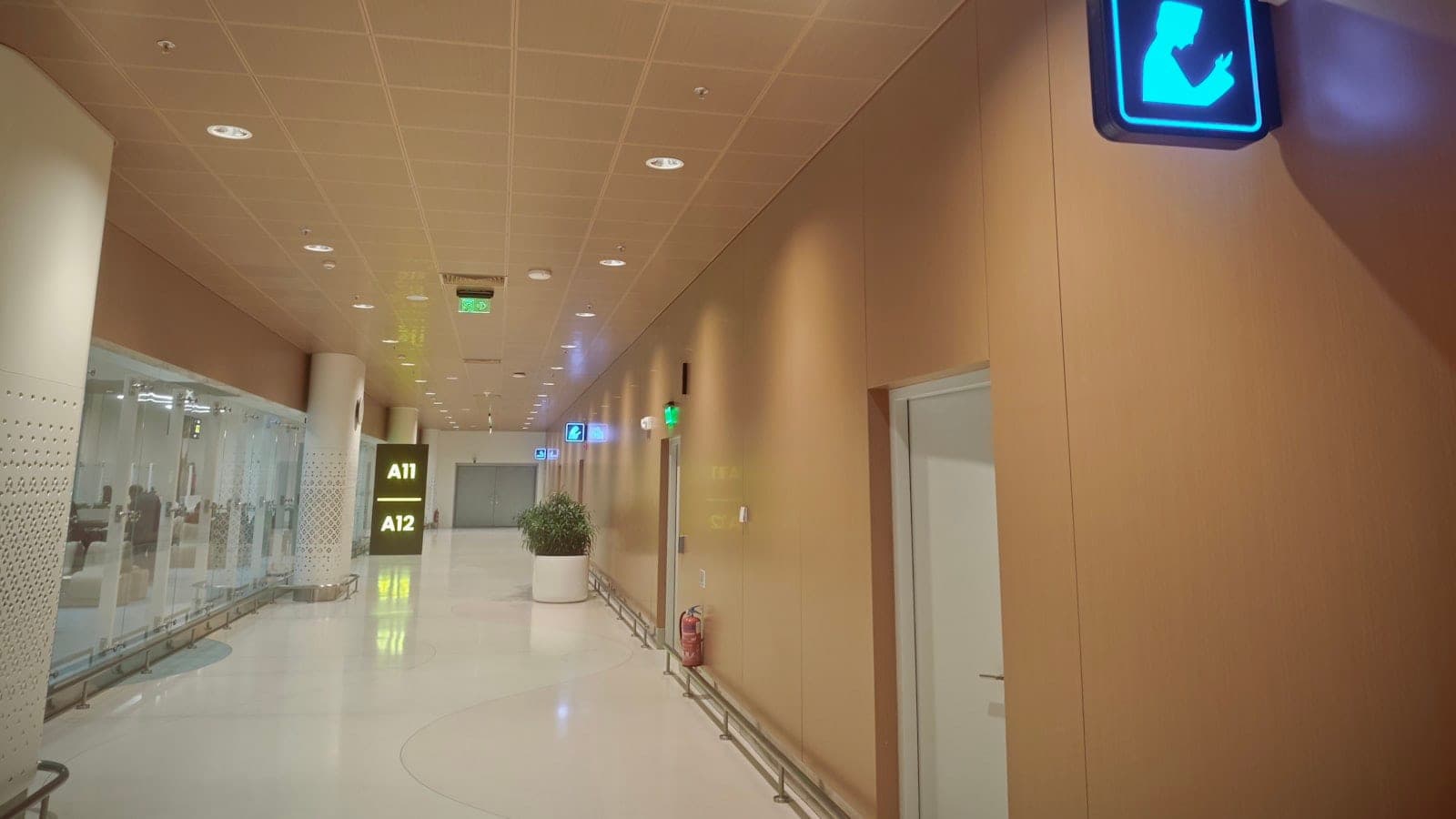 Passagers marchant dans un couloir de correspondance vitré, panneau indiquant la direction des portes B et C