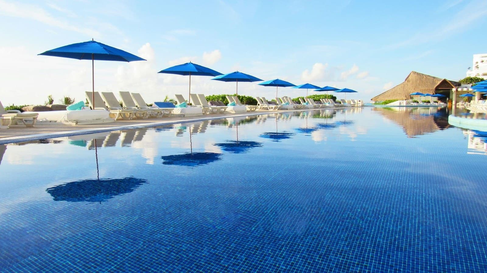 Piscine à débordement et parasols bleus face à la mer, au Live Aqua Cancún
