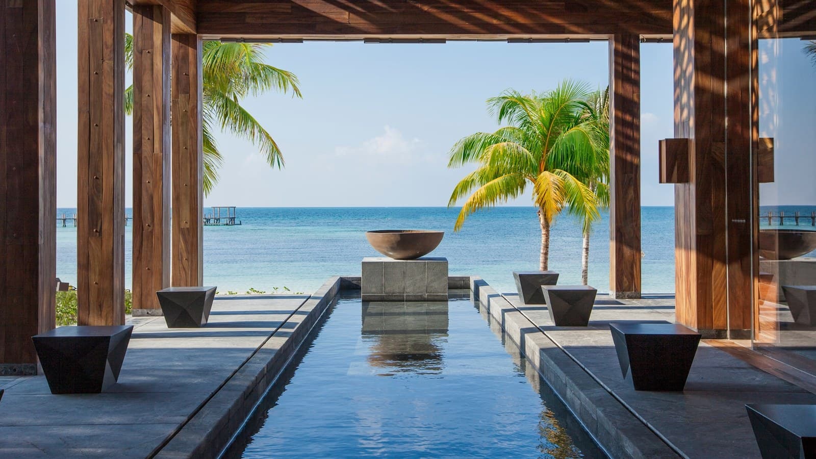 Pavillon ouvert sur la mer des Caraïbes, bassin réfléchissant et palmiers, au NIZUC