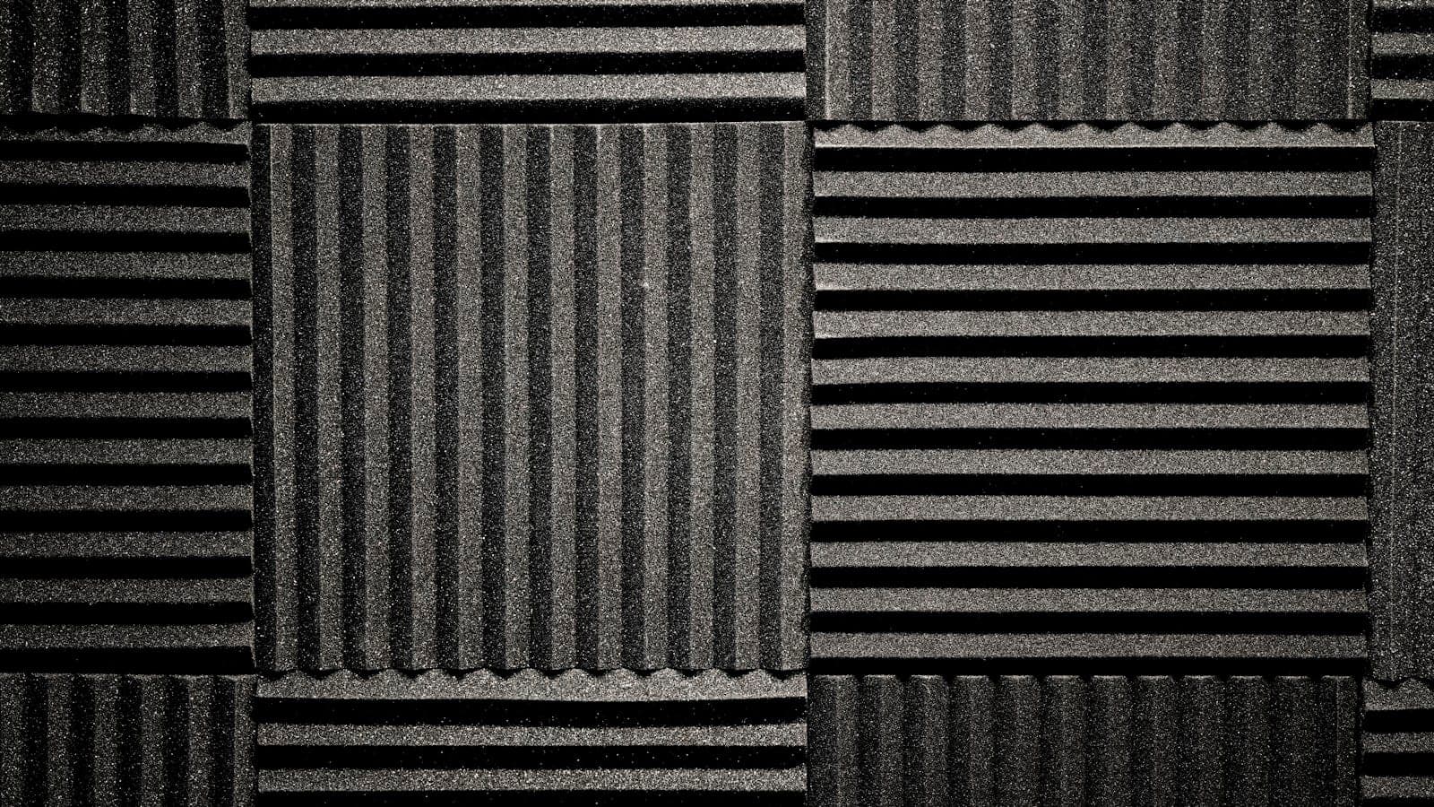 Bureau de douze metres carres avec panneaux absorbants sur le mur lateral, rideau epais devant la fenetre et tapis a poils longs sous le siege