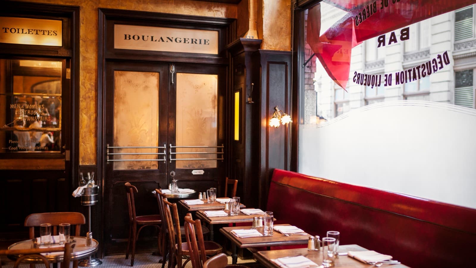 La salle de Balthazar à SoHo, ses banquettes de cuir rouge et sa porte Boulangerie, le long de la vitrine sur Spring Street