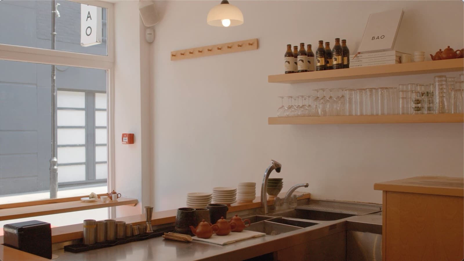 Le comptoir de BAO Soho baigné de lumière, étagères de bois clair, théières en terre cuite et vitrine sur Lexington Street