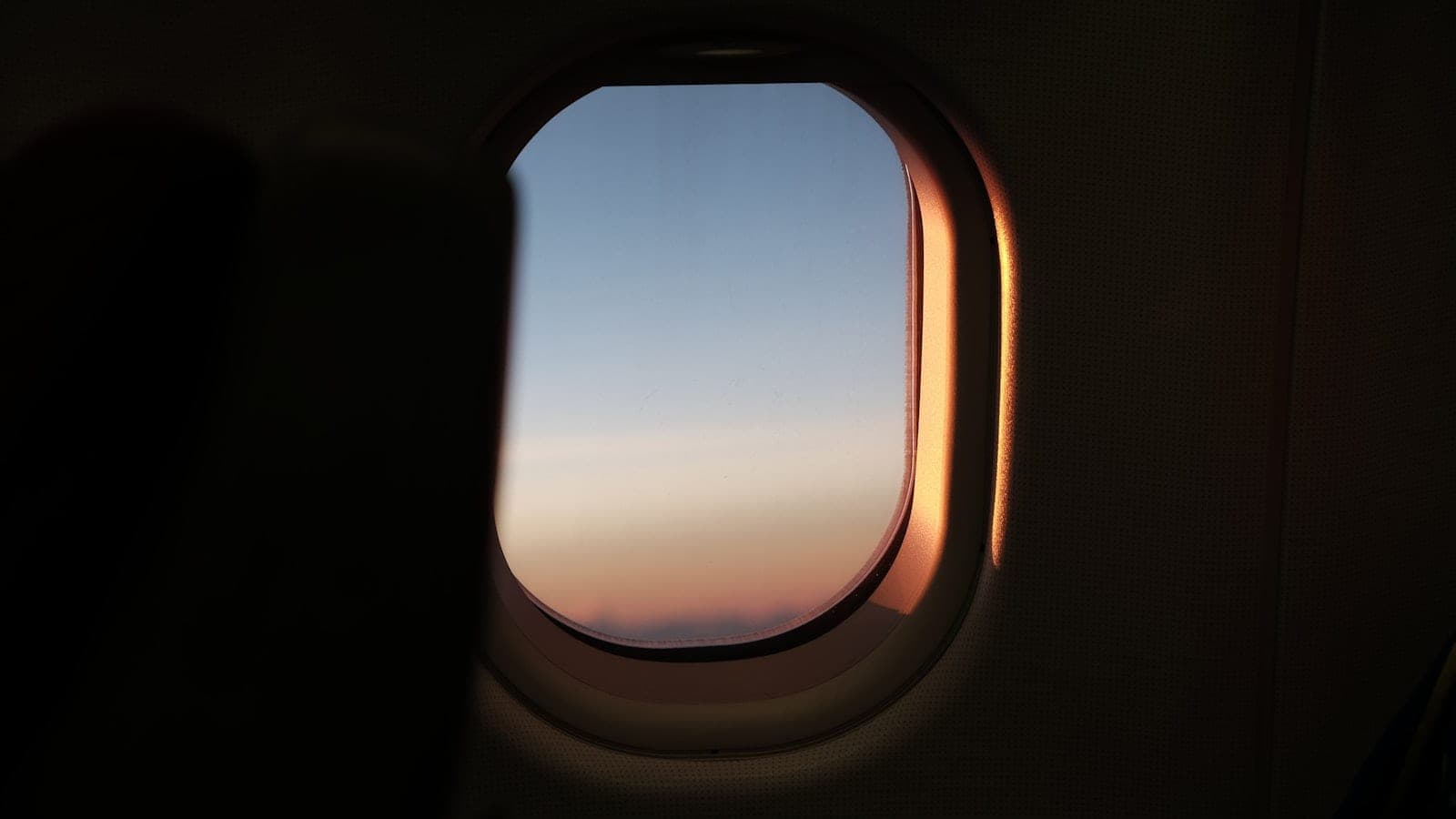 Cabine d'avion de nuit, hublot obturé, voyageur consultant une montre affichant deux fuseaux horaires