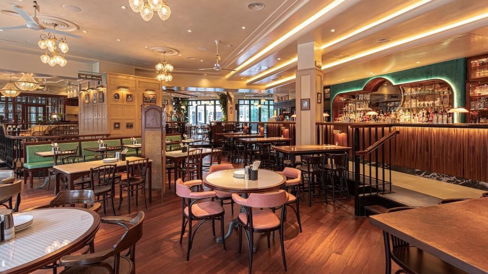 La grande salle de Dishoom Covent Garden, chaises bistrot, lustres de verre et bar voûté de velours vert