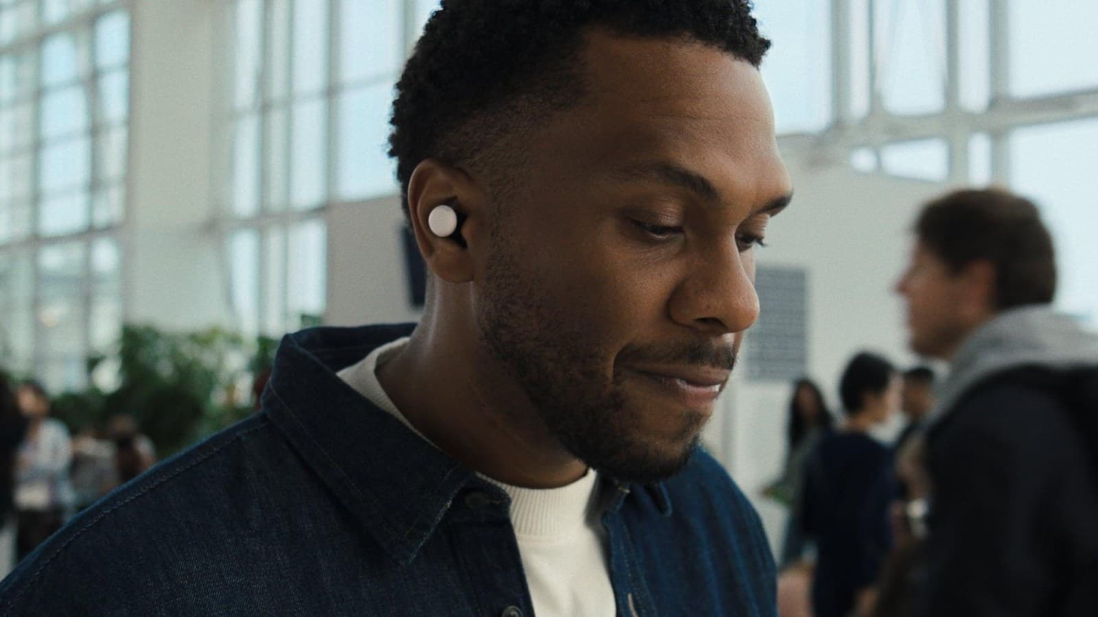 Homme dans un hall d'aéroport portant des Google Pixel Buds Pro 2