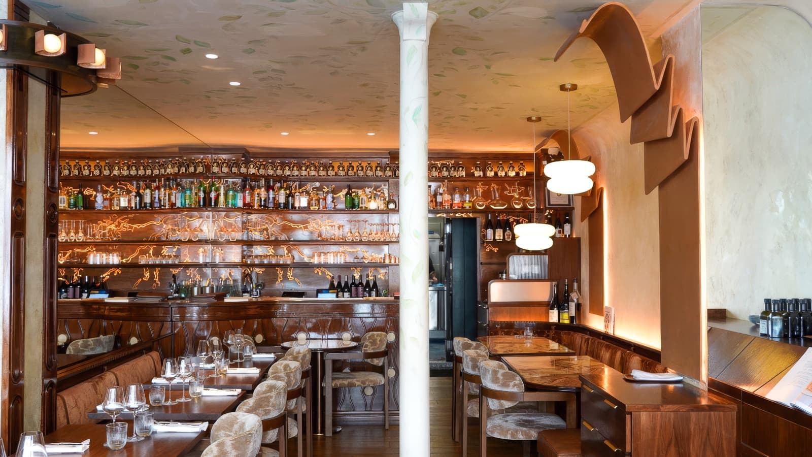 La salle d'IDA, son bar en bois verni, sa colonne blanche et son plafond peint de feuillages