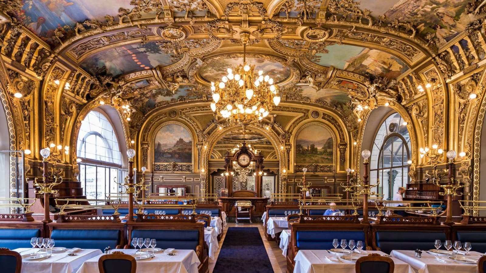 La grande salle du Train Bleu, plafonds peints, dorures, lustre et banquettes bleues, au premier étage de la gare de Lyon à Paris