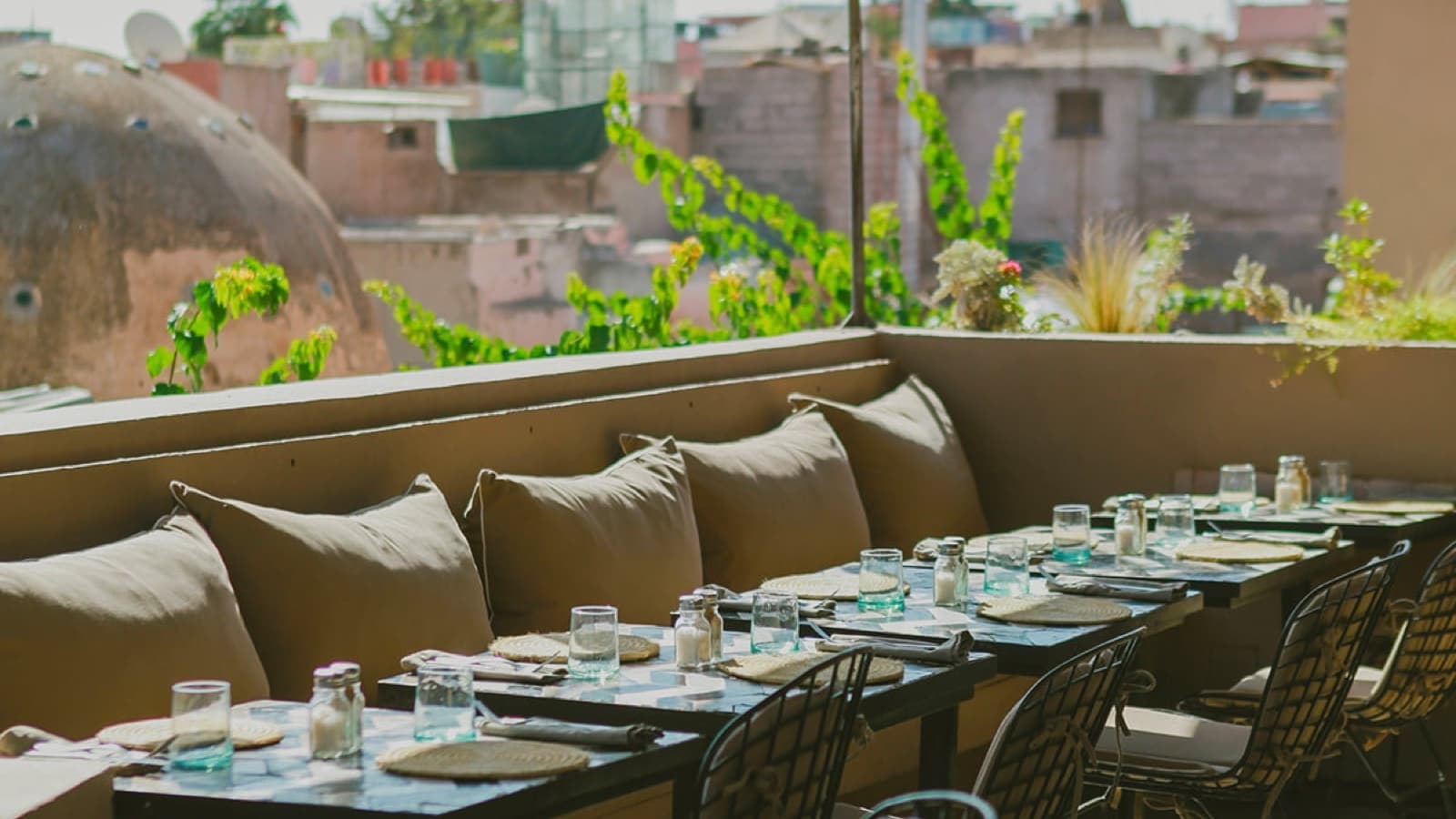 Une des terrasses de Nomad, banquettes et coussins écrus face aux toits de la médina de Marrakech