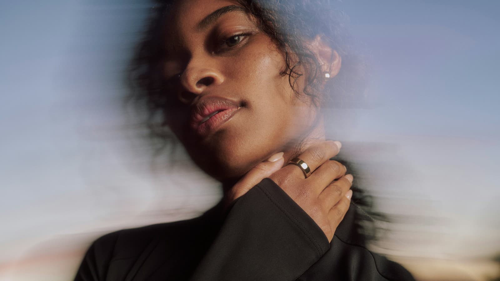 Femme portant l'Oura Ring 5 à la main, la bague visible contre la lumière