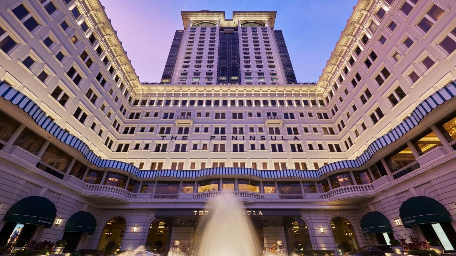 Façade du Peninsula Hong Kong sur Salisbury Road, avec la tour de 1994 en arrière-plan et deux Rolls-Royce vertes alignées devant le porche