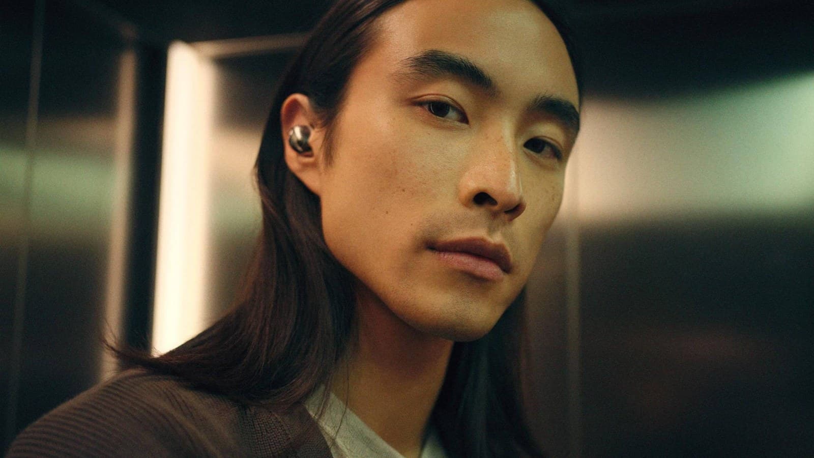 Homme aux cheveux longs portant un écouteur Sennheiser Momentum True Wireless 5