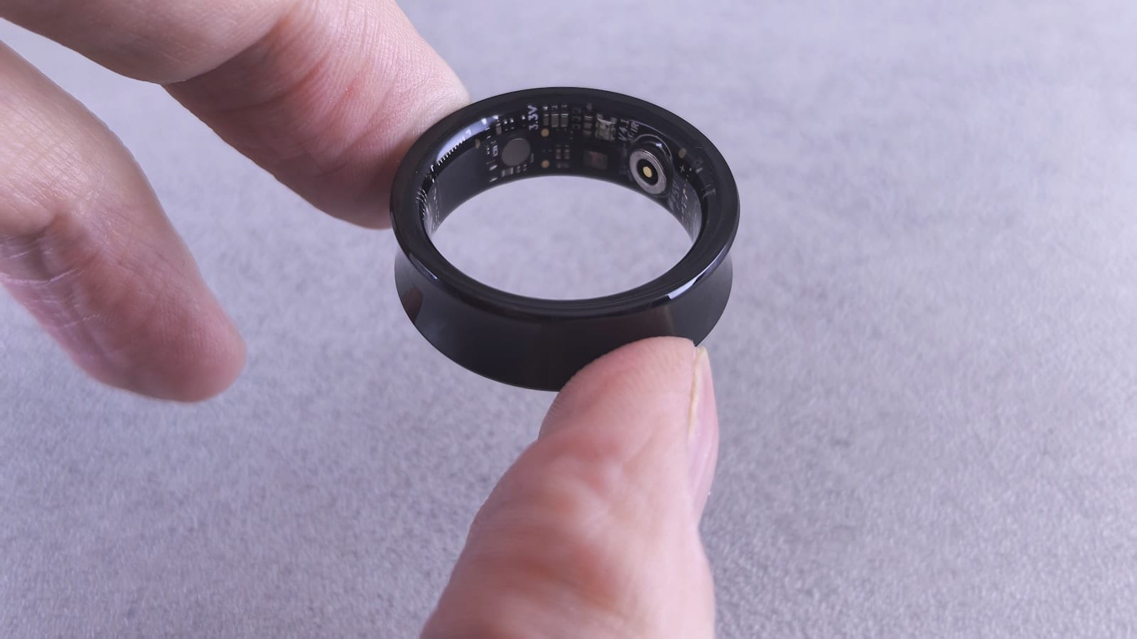 Une bague connectée, un bracelet et un boîtier de capteur sous-matelas posés sur une table de chevet d'hôtel, à côté d'un enregistreur portable