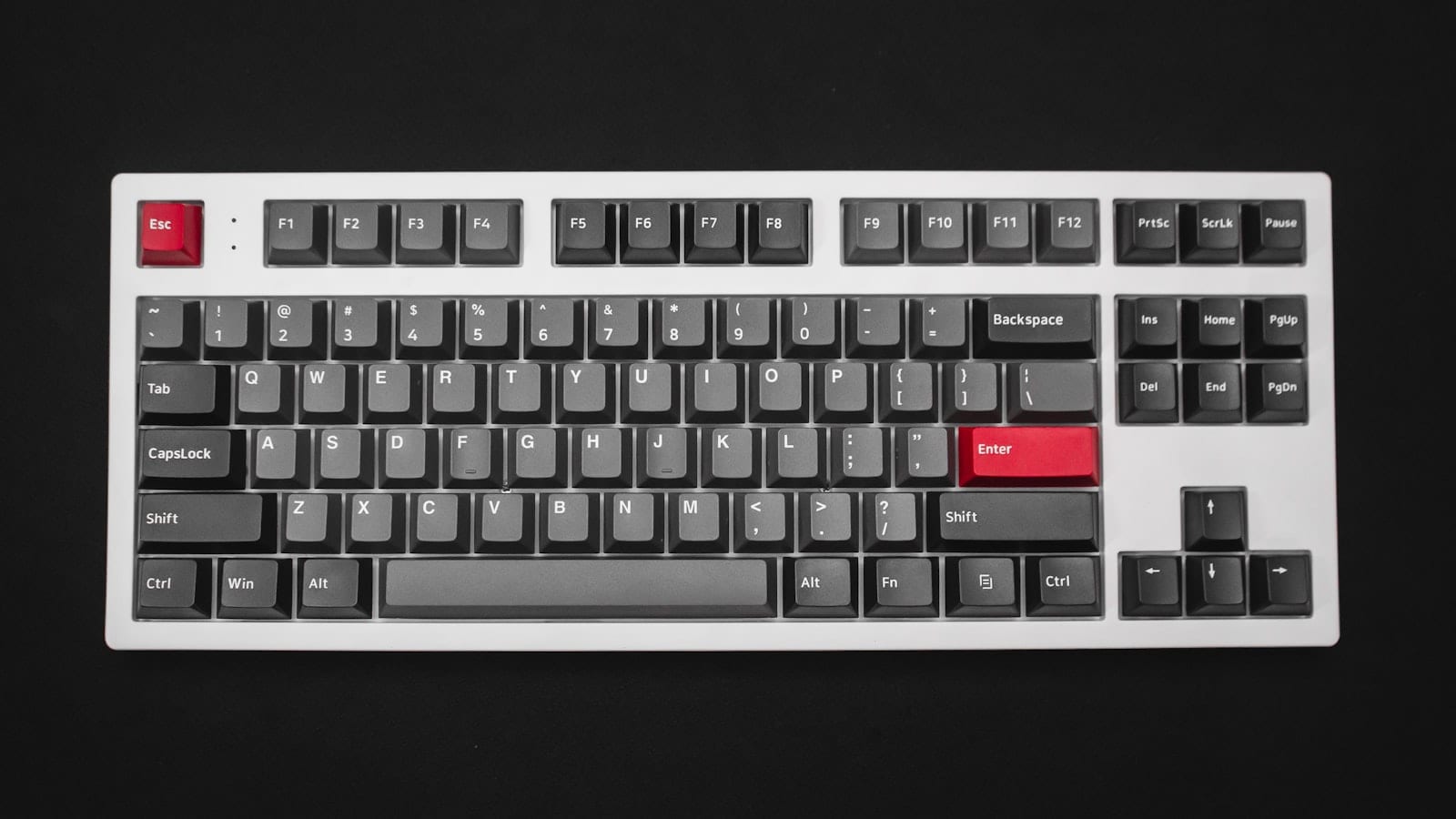 Un clavier compact au format 65 % posé sur une tablette de siège de train, à côté d'un ordinateur portable fermé et d'un carnet ouvert.