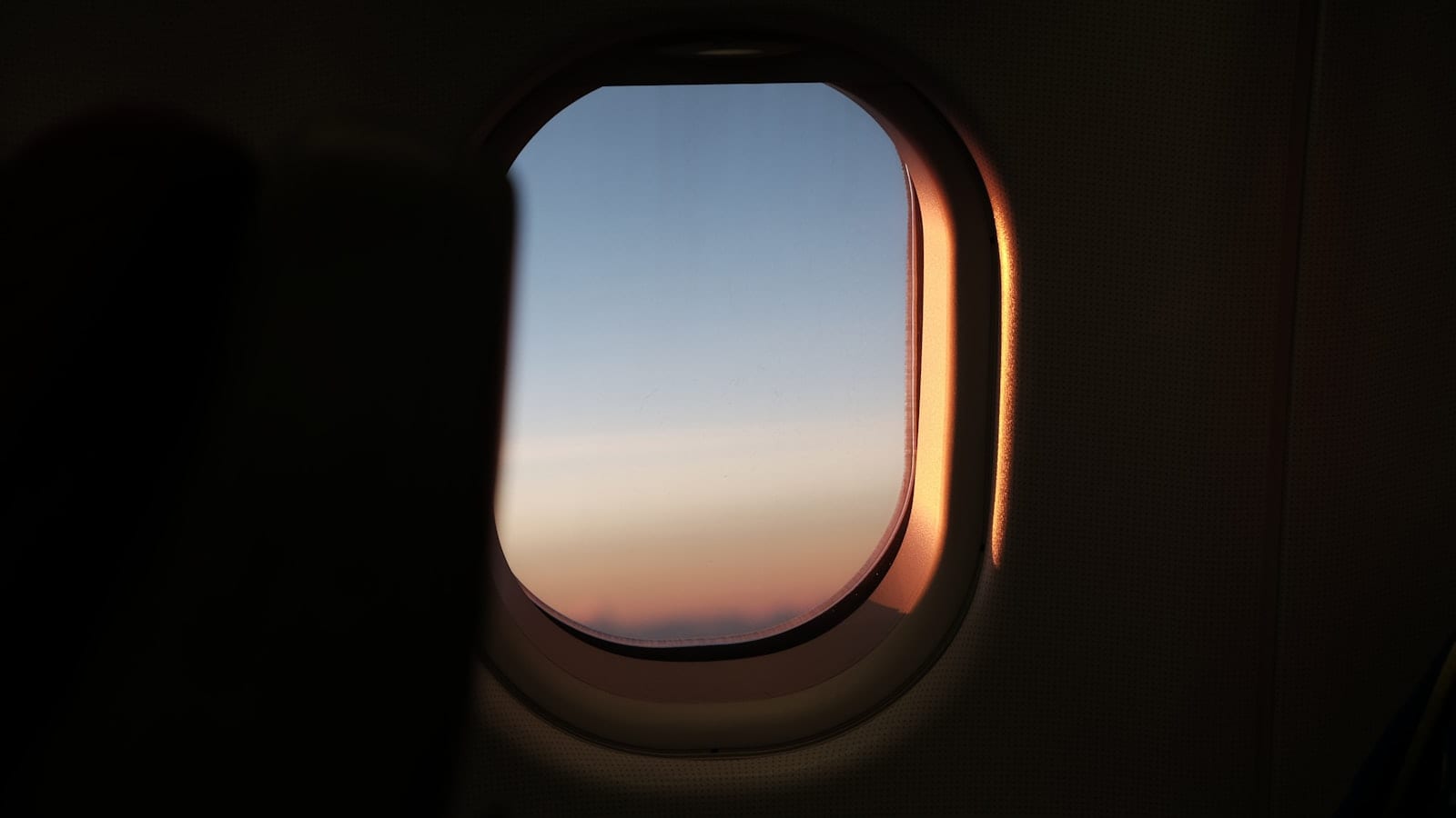 Cabine d'avion de nuit, hublot obturé, voyageur consultant une montre affichant deux fuseaux horaires