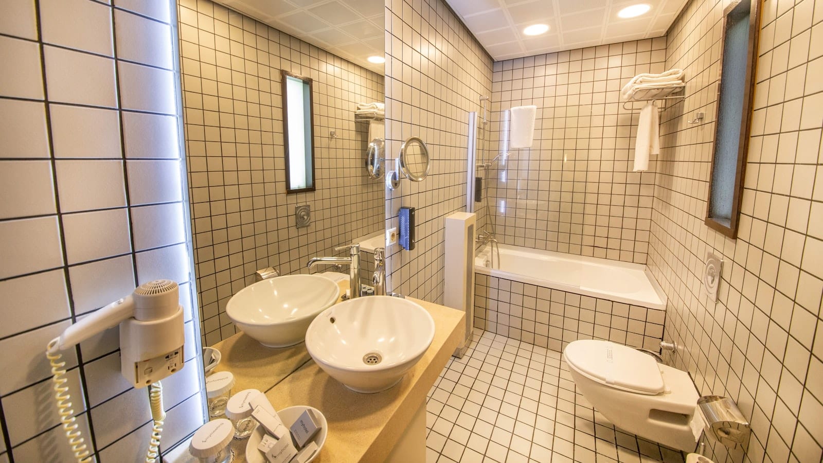 Chemise blanche en popeline suspendue à un cintre accroché à la tringle de douche d'une salle de bains d'hôtel, buée sur le miroir
