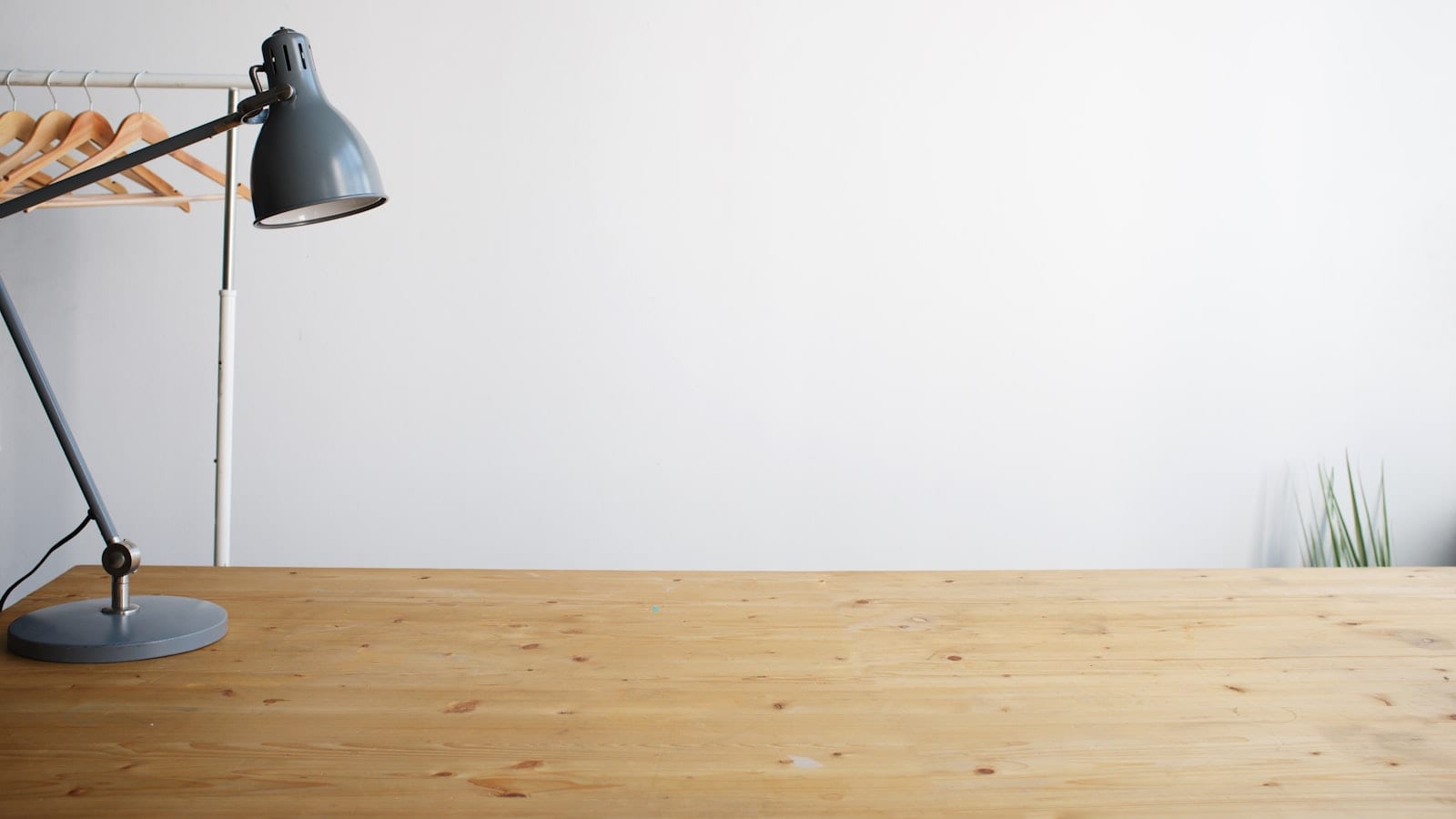 Bureau vu de trois quarts avec un panneau LED pose a gauche de la webcam, une lampe d'appoint derriere l'ecran et une fenetre voilee sur le cote