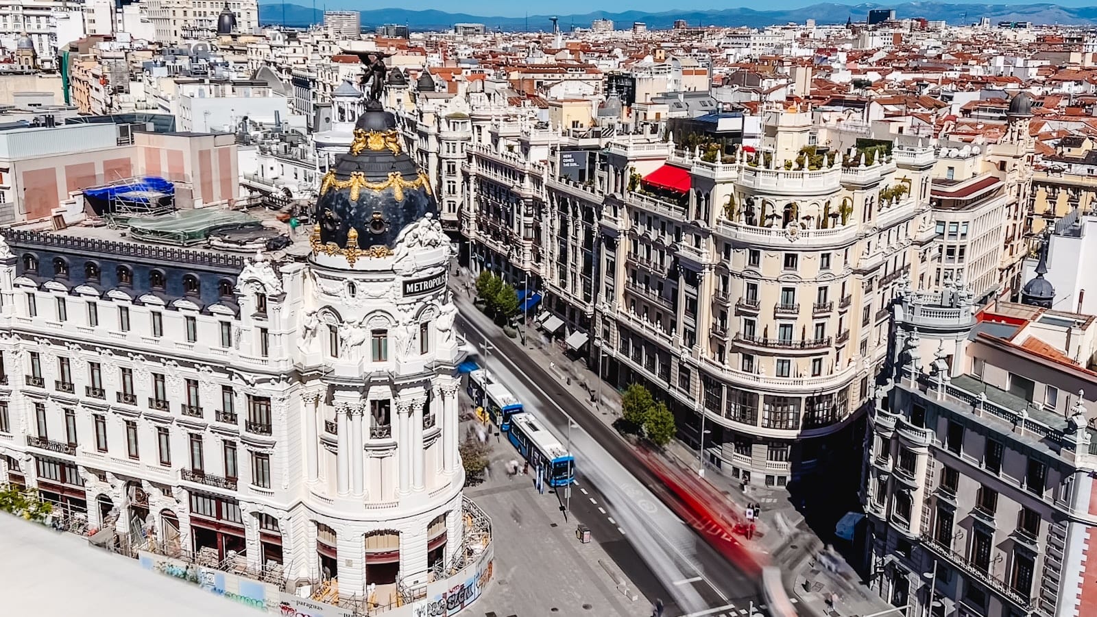 Terrasse d'un café du quartier de Chamberí à Madrid en fin de matinée, un ordinateur portable ouvert sur une table ronde en marbre et un carnet de notes à côté