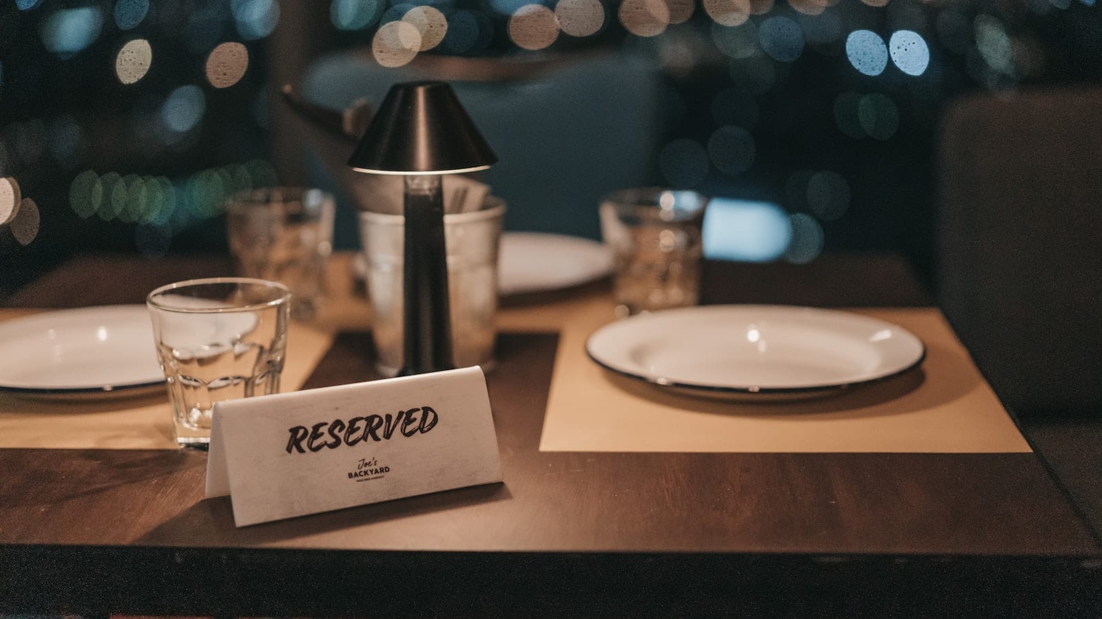 Salle de restaurant en fin de service de midi, tables dressées avec nappes blanches, un téléphone fixe posé sur le pupitre d'accueil