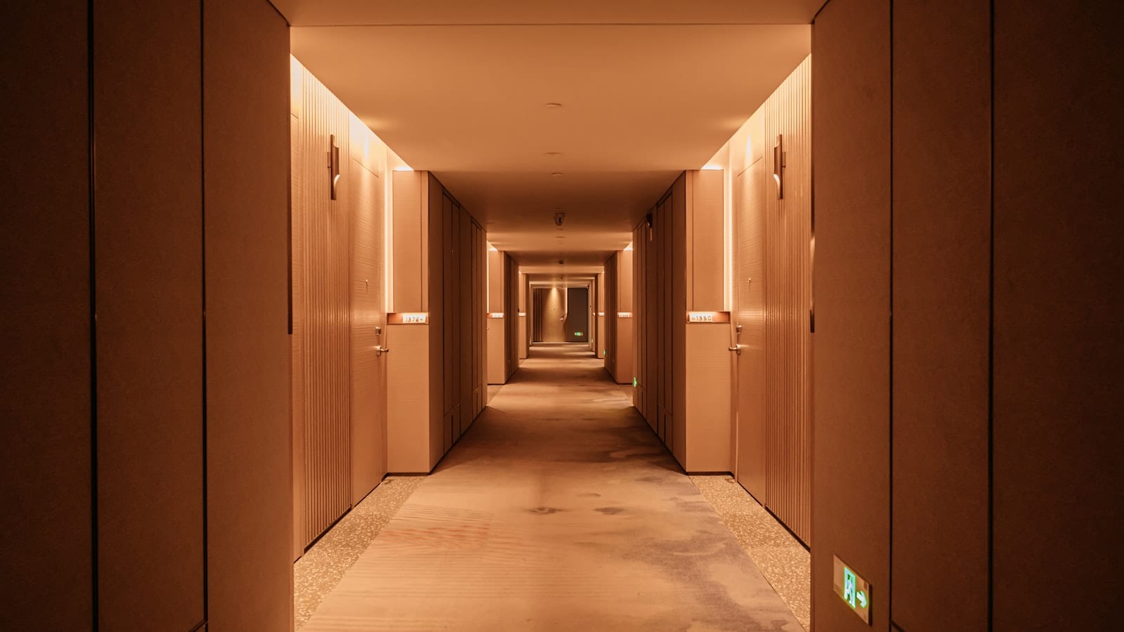 Comptoir de réception d'un hôtel d'affaires européen au petit matin, trois cartes de fidélité posées à côté d'une valise cabine