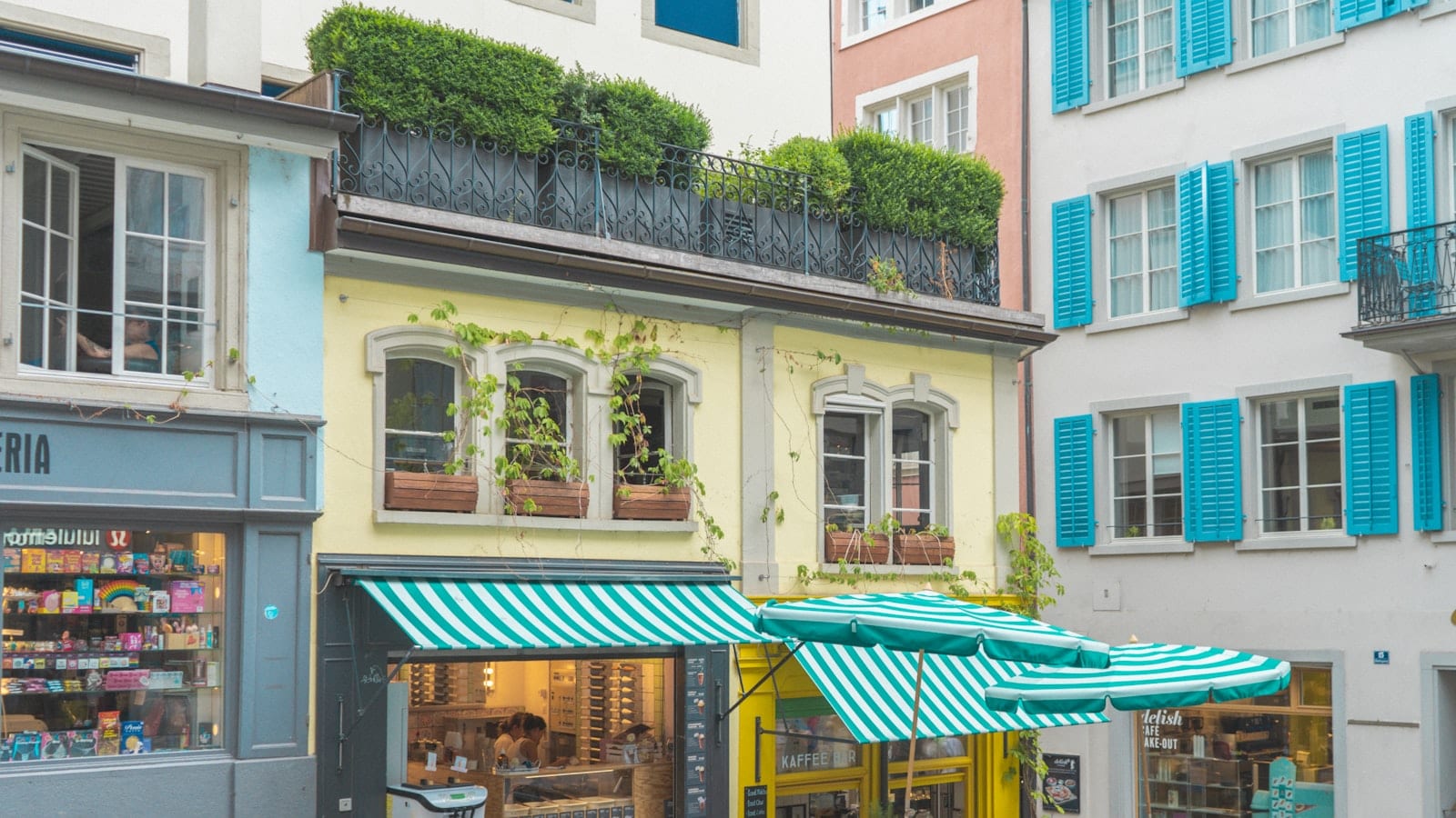 Table de bistrot zurichois en bois clair avec deux assiettes du jour, une carafe d'eau et un carnet de notes, vue plongeante en milieu de journée