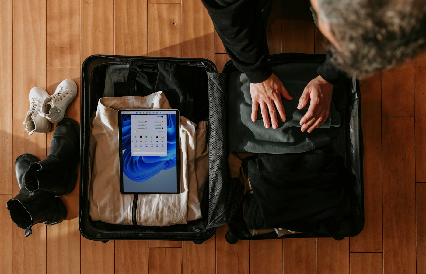 Valise cabine rigide ouverte sur un lit d'hôtel, cinq cubes de rangement en nylon coloré alignés à côté, dont deux fermés par une fermeture éclair de compression