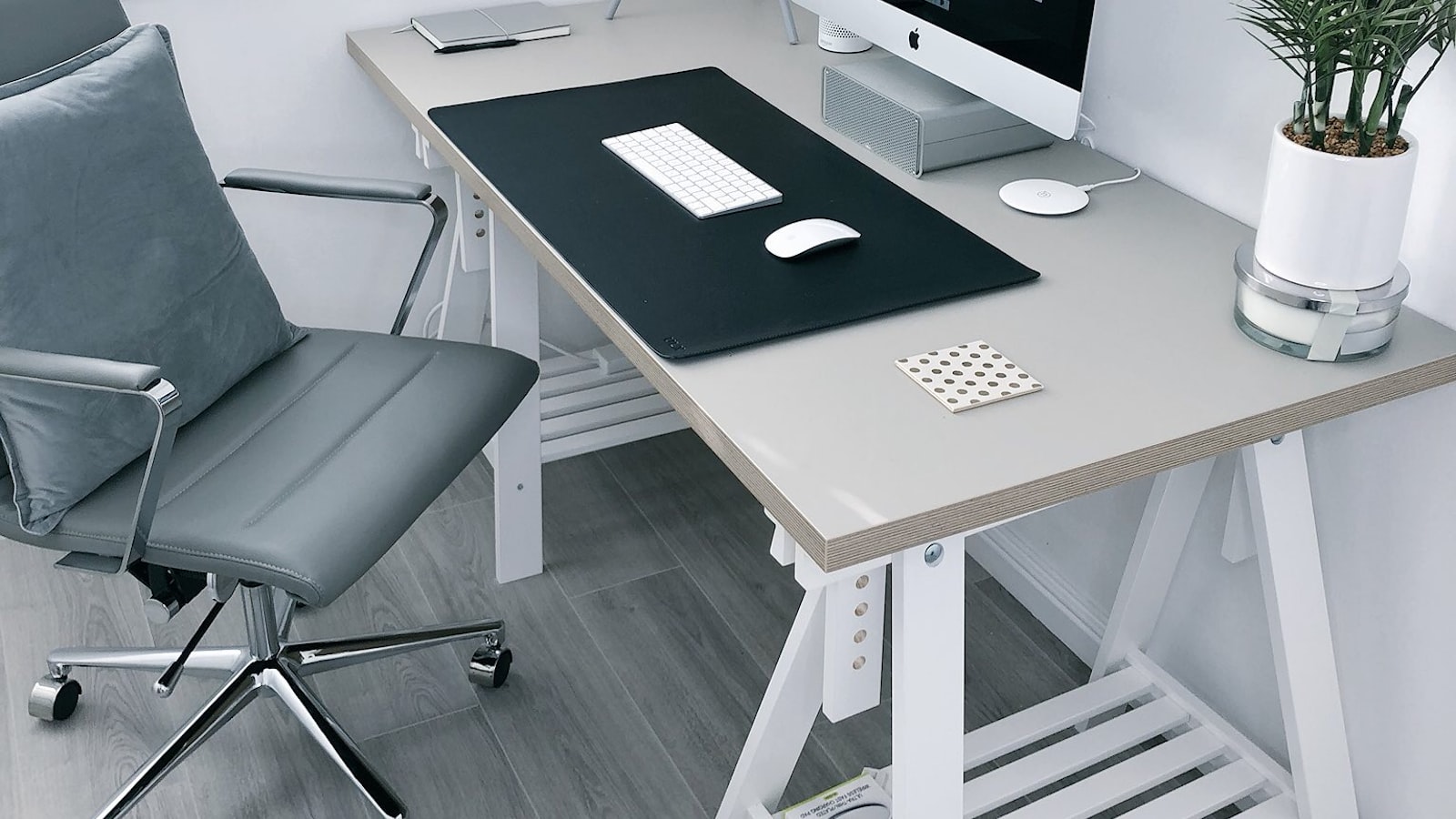 Bureau assis-debout en position haute dans un bureau lumineux, avec deux ecrans montes sur un bras articule et une regle posee contre le pietement