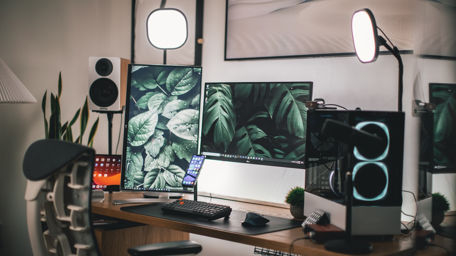 Bureau vu de trois quarts avec un panneau LED pose a gauche de la webcam, une lampe d'appoint derriere l'ecran et une fenetre voilee sur le cote