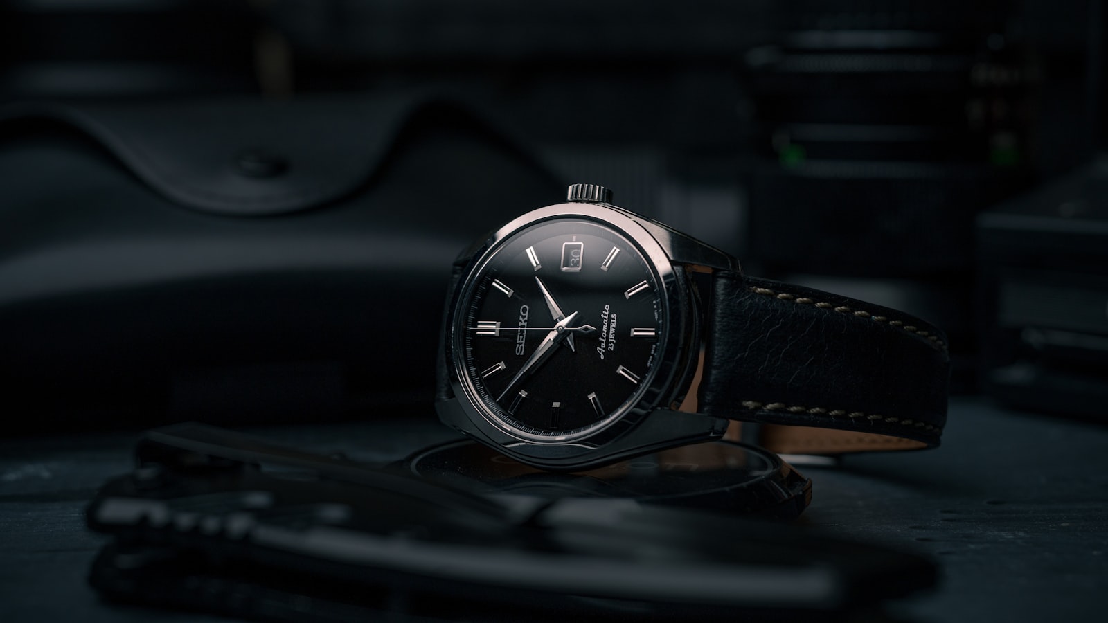 Quatre montres automatiques posées côté fond transparent sur un tapis d'horloger, rotors visibles, à côté d'un chronomètre de contrôle