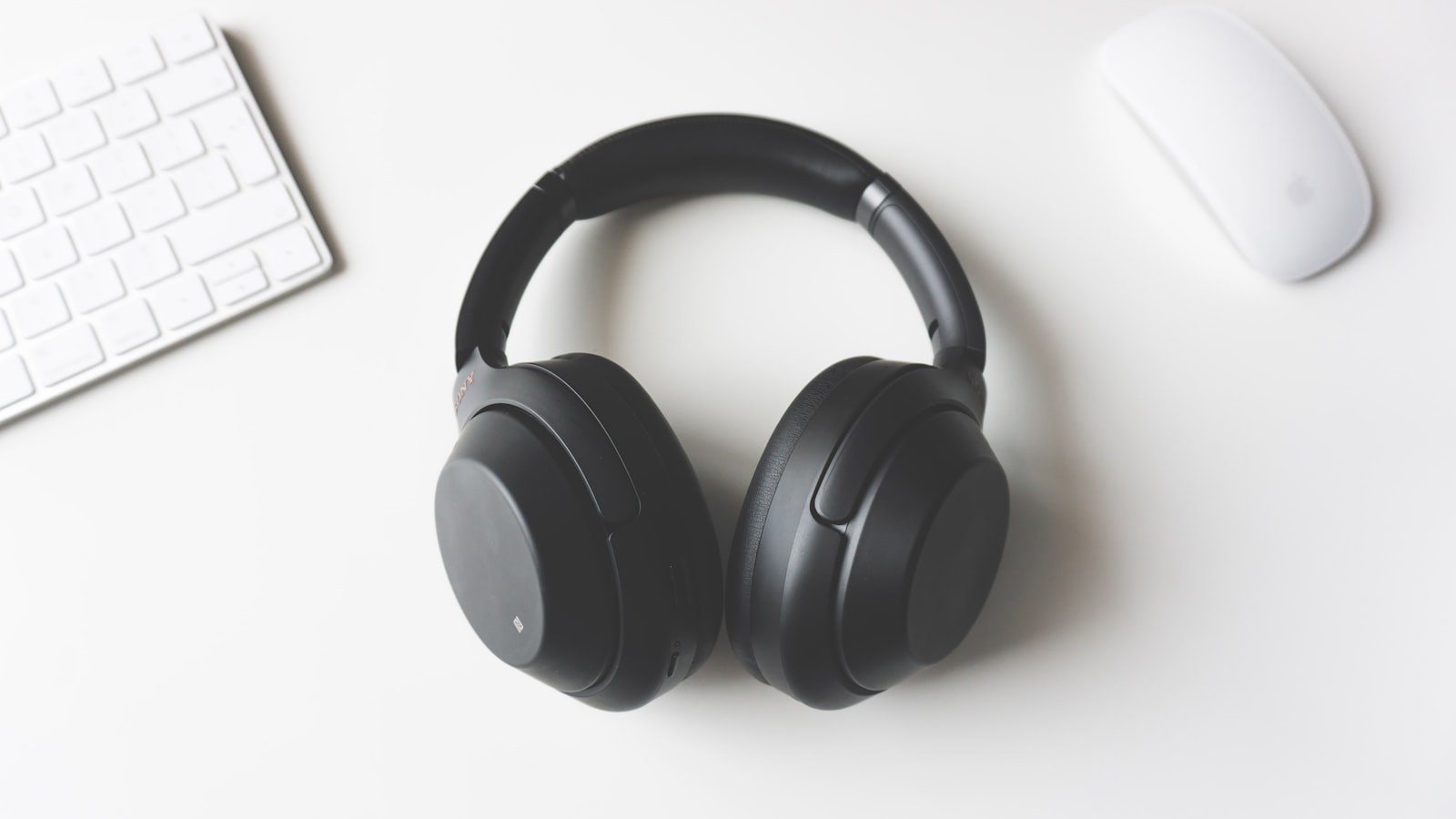 Cinq paires d'écouteurs intra-auriculaires posées sur une tablette de siège d'avion, boîtiers ouverts, hublot en arrière-plan