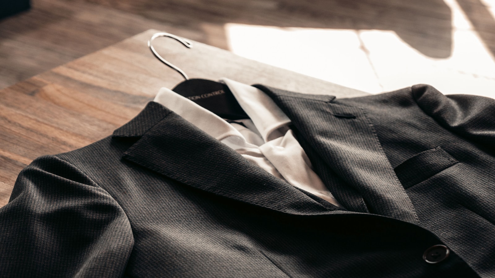 Cinq pantalons de couleur sombre posés à plat côte à côte sur une table en bois clair, avec une étiquette numérotée sur chaque ceinture